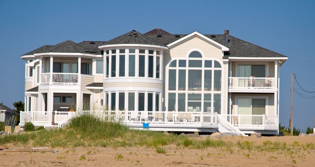 A large white house with a asphalt roof type sand and a swimming pool